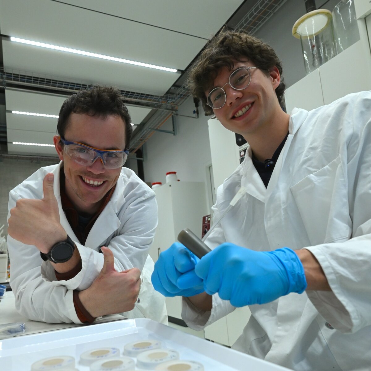 Two expedition researchers in white laboratory coats working with samples.